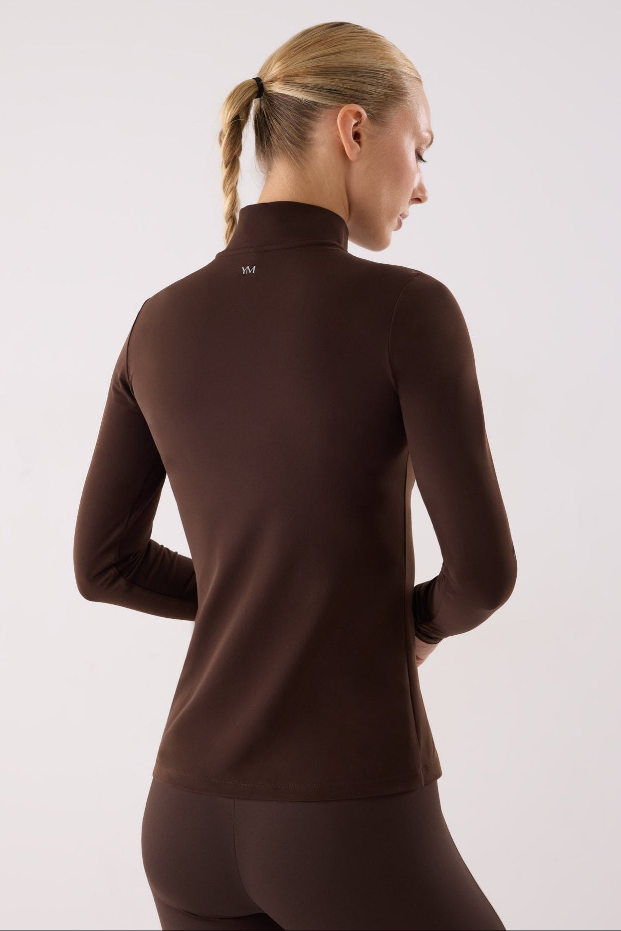 camiseta deportiva manga larga con media cremallera gimnasio en marrón dark chocolate vista en movimiento para entrenamientos tejido transpirable con interior afelpado